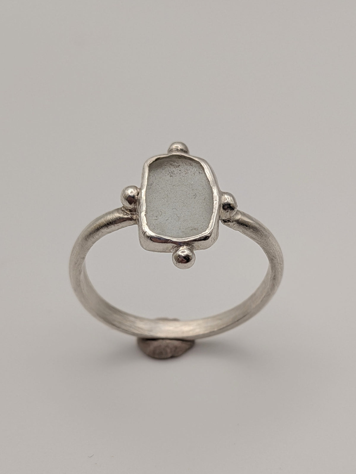 Clear sea glass bubble ring in a handmade sterling silver setting with a fine silver bezel by All Our Light.