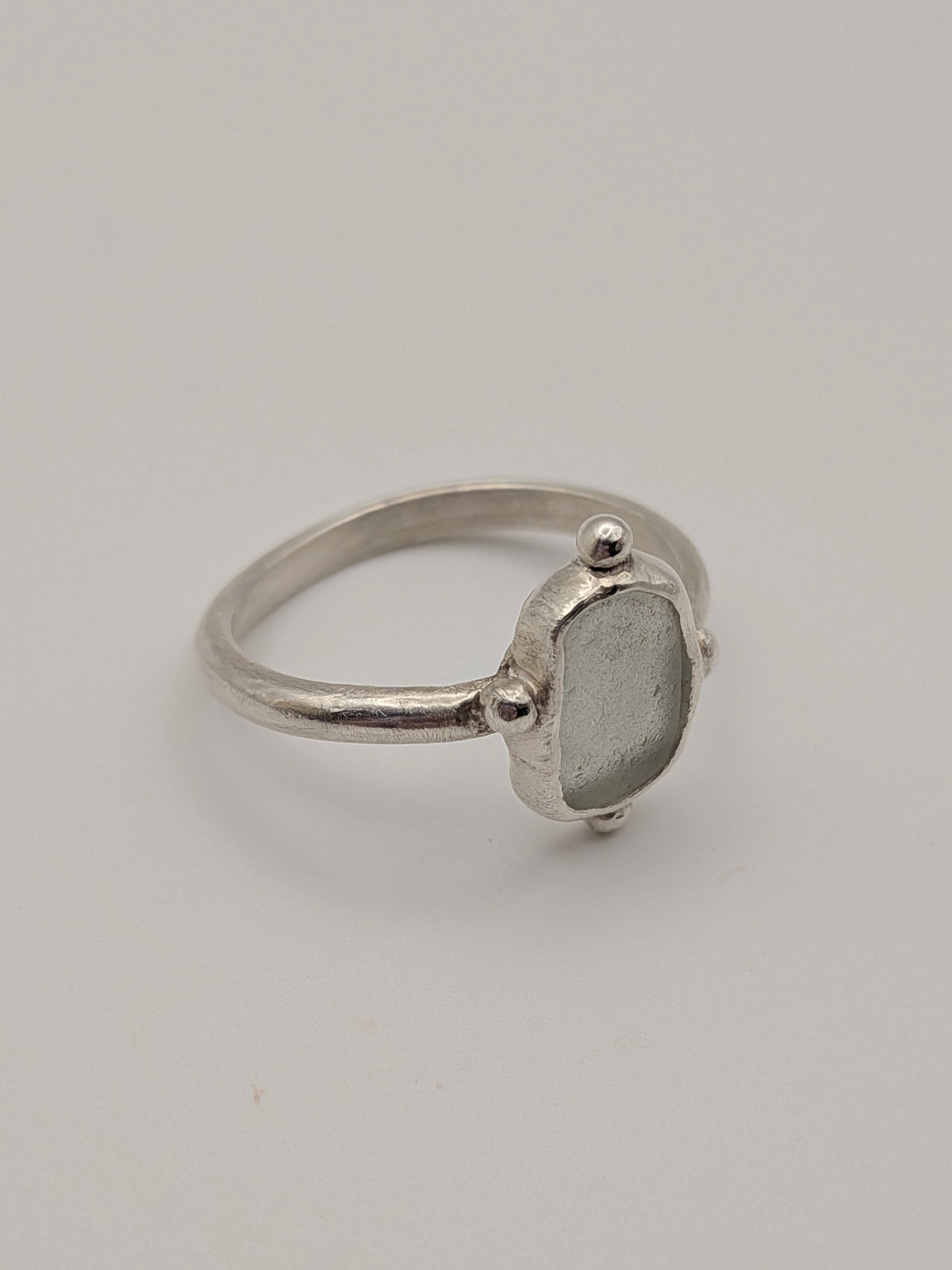 Clear sea glass bubble ring in a handmade sterling silver setting with a fine silver bezel by All Our Light.