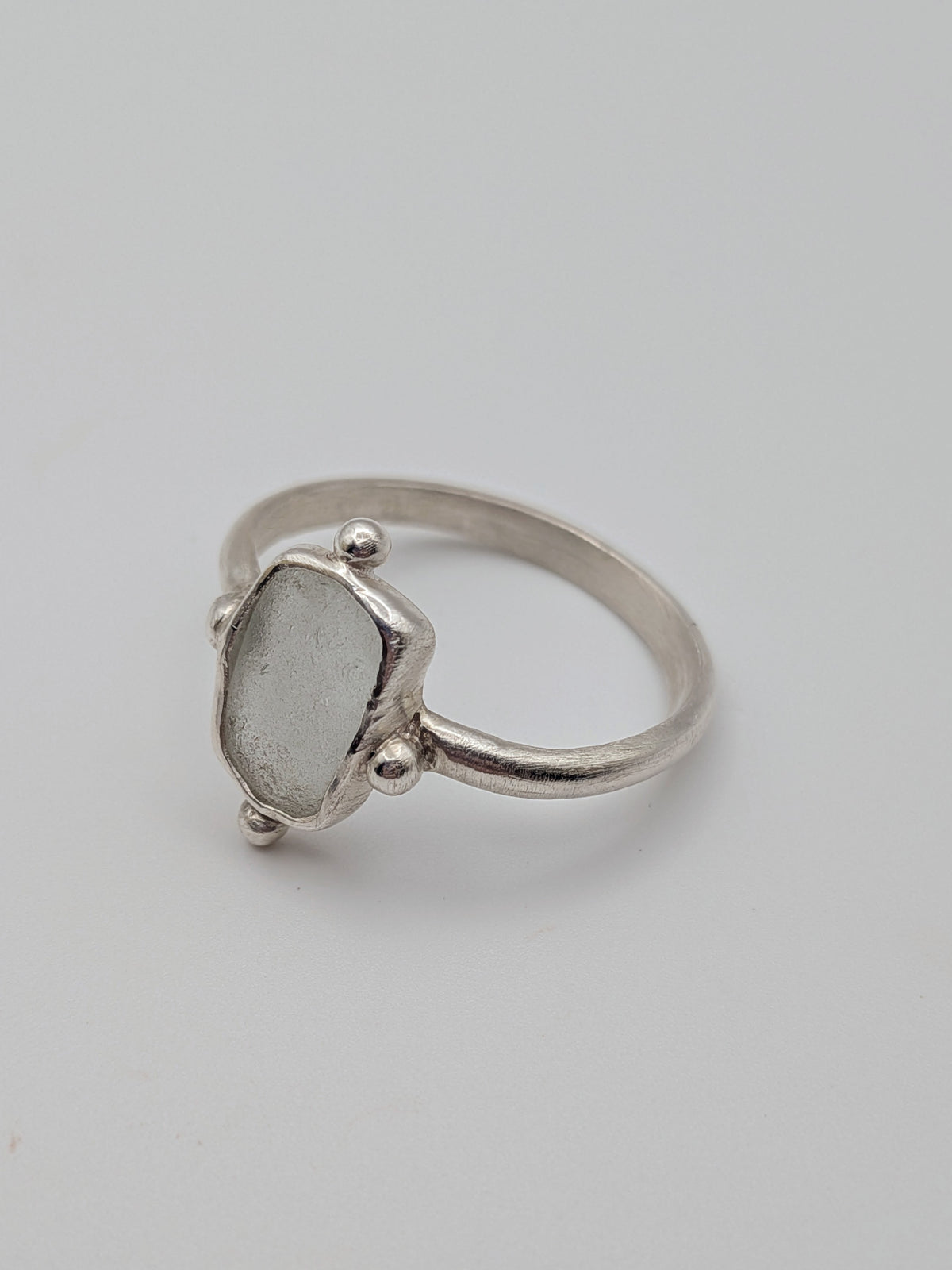 Clear sea glass bubble ring in a handmade sterling silver setting with a fine silver bezel by All Our Light.